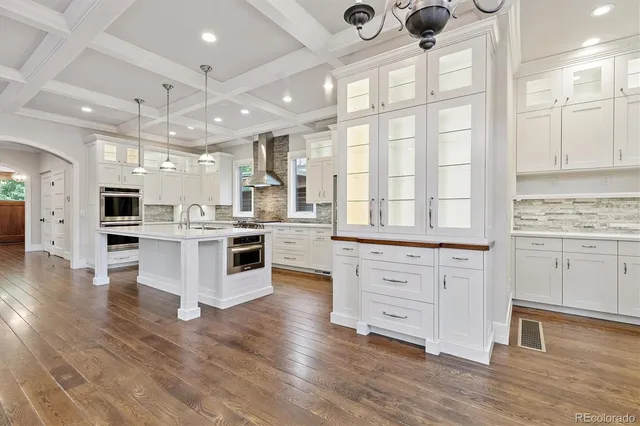 a kitchen with stainless steel appliances kitchen island granite countertop a stove a sink and white cabinets with wooden floor