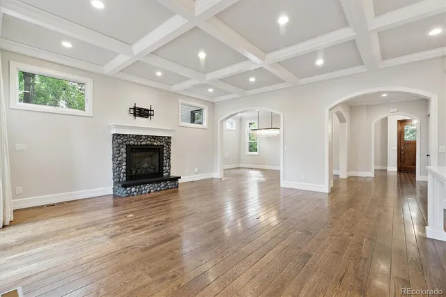 an empty room with wooden floor a fireplace and windows