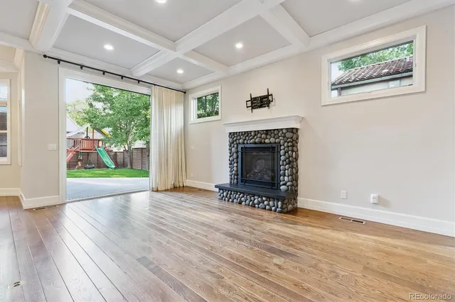 a view of an empty room with wooden floor and a fireplace