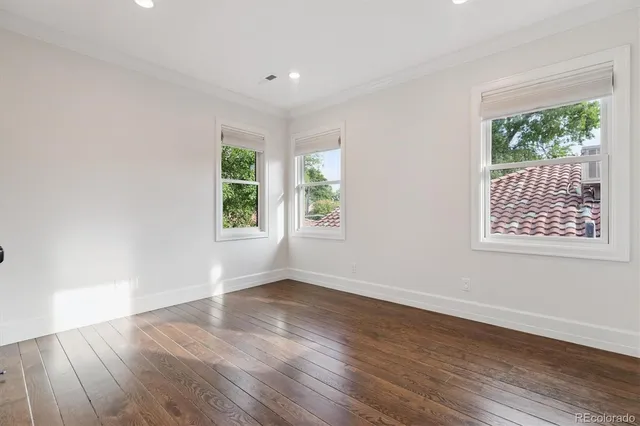 a view of an empty room with wooden floor and windows