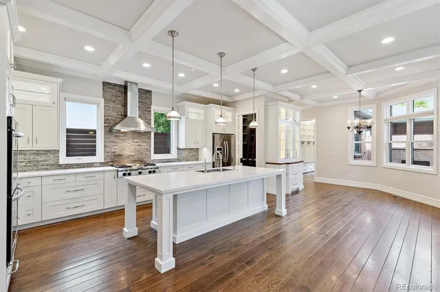 a large white kitchen with lots of counter space a sink appliances and cabinets