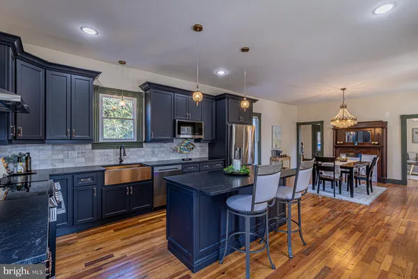 a large kitchen with cabinets chairs and refrigerator