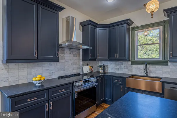 a kitchen with stainless steel appliances granite countertop a sink a stove cabinets and wooden floor