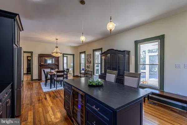 a kitchen with stainless steel appliances granite countertop a stove a refrigerator a dining table and chairs with wooden floor