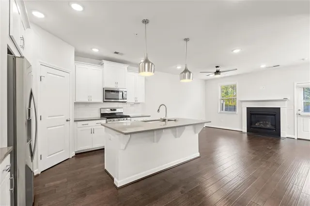 a kitchen with stainless steel appliances granite countertop a sink a stove a refrigerator and a oven with wooden floor