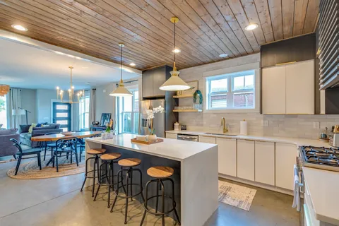 a kitchen with stainless steel appliances granite countertop a sink a stove a refrigerator and island with wooden floor