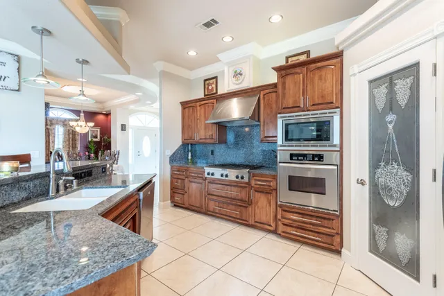 a kitchen with stainless steel appliances kitchen island granite countertop a refrigerator a stove a dining table and chairs