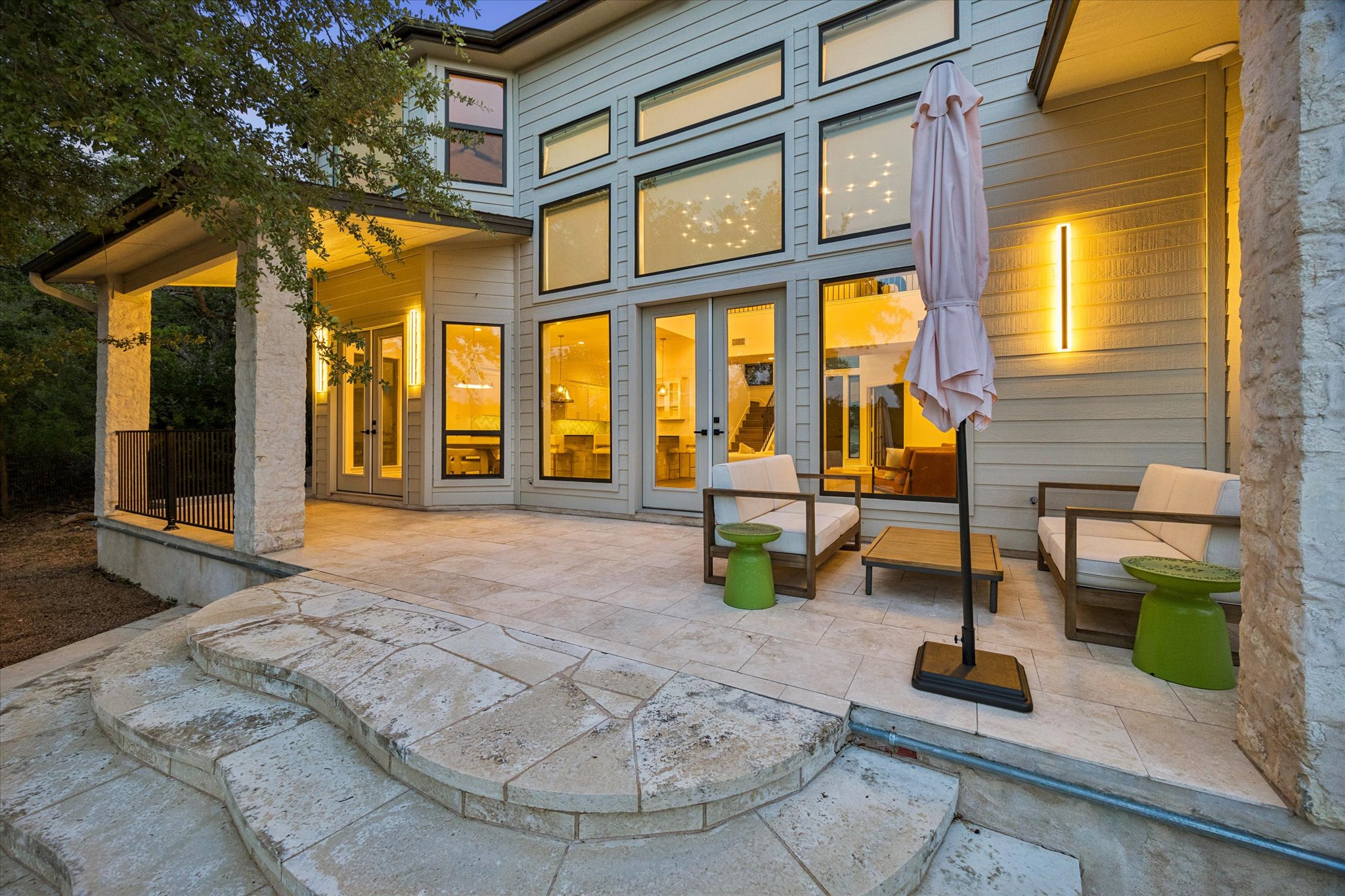 3719 Bee Creek Road Spicewood, TX 78669 - Photo 33 of 40 An inviting outdoor patio with elegant stone steps leads to an entertainment space with ample natural light from extensive glass windows.