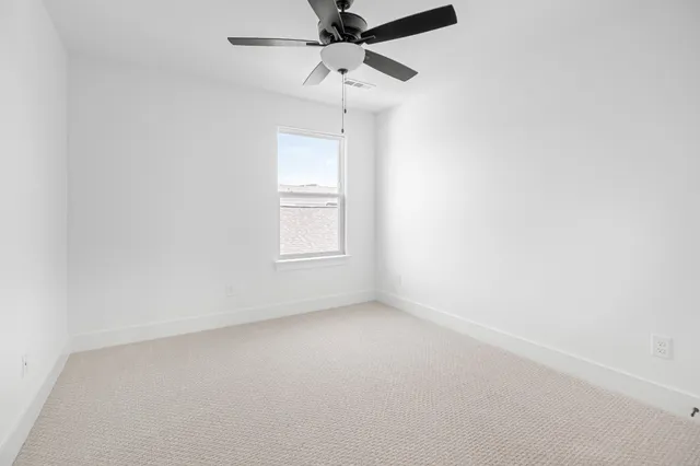 an empty room with a window and a fan