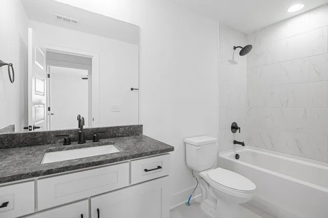 a bathroom with a granite countertop sink a toilet and a bathtub