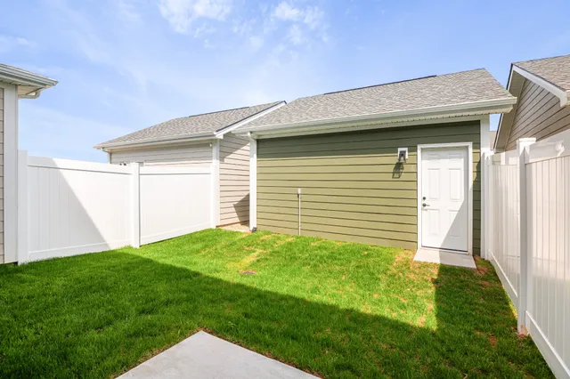 a backyard of a house with plants and wooden fence
