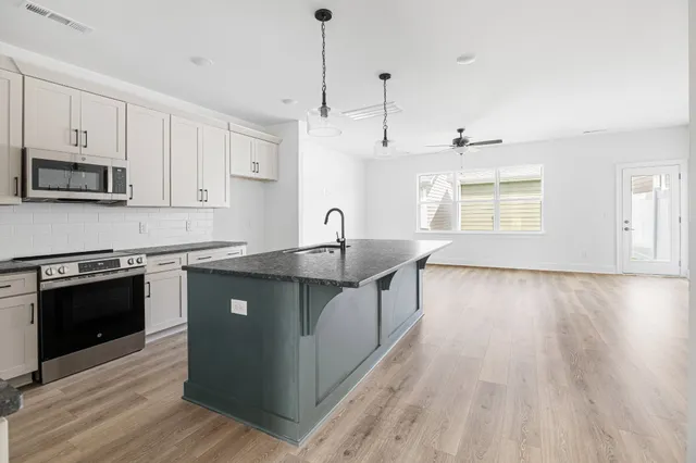 a kitchen with stainless steel appliances granite countertop a sink a stove and a wooden floor