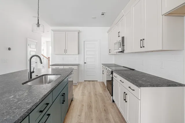 a kitchen with granite countertop a sink stove and cabinets