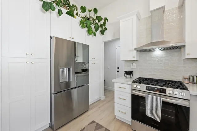 a kitchen with stainless steel appliances a refrigerator a stove a sink and white cabinets