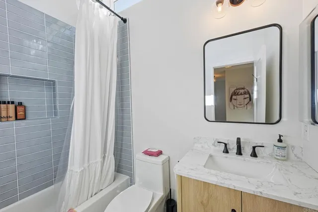 a bathroom with a granite countertop sink vanity mirror and toilet