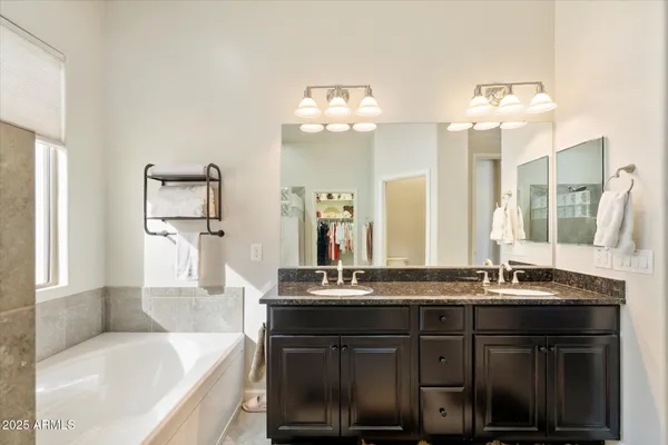 a bathroom with a granite countertop bathtub a sink and a mirror