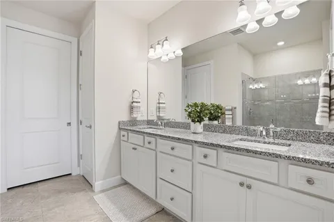 a bathroom with a granite countertop double vanity sink and a mirror