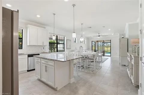 a kitchen with stainless steel appliances kitchen island a table chairs in it and white cabinets