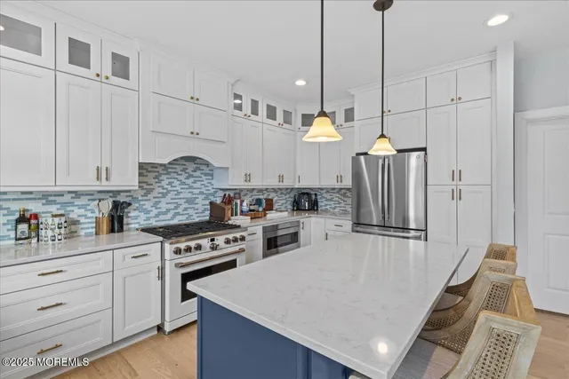 a kitchen with refrigerator a stove and white cabinets with wooden floor