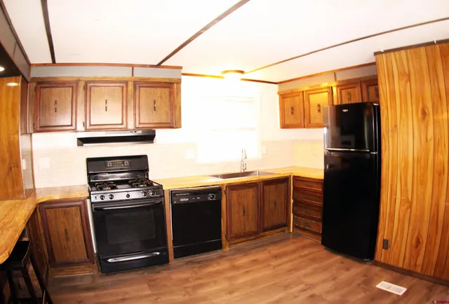 a kitchen with granite countertop a refrigerator stove and sink
