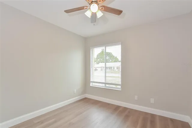 an empty room with a window and a fan