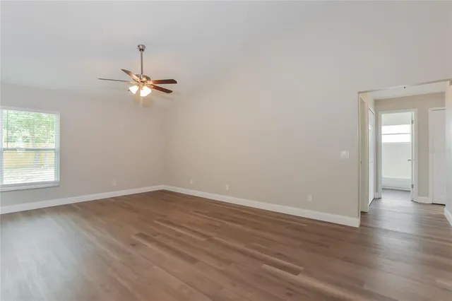 an empty room with wooden floor fan and window