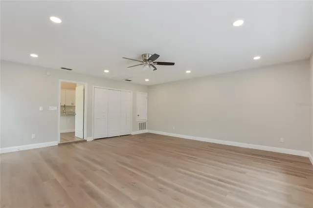 an empty room with wooden floor and a ceiling fan