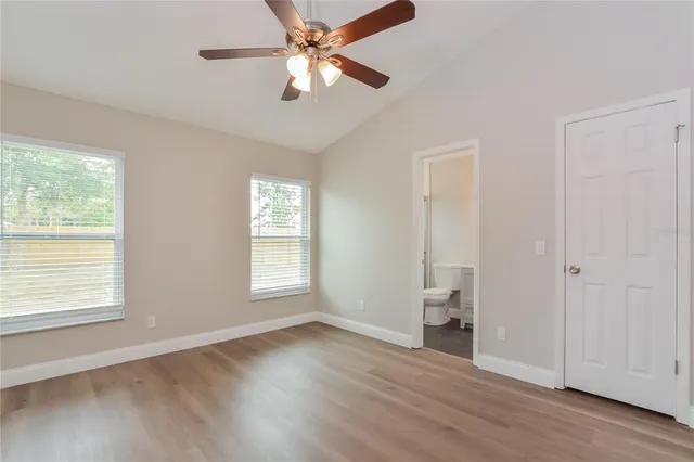 a view of an empty room with a window and wooden floor