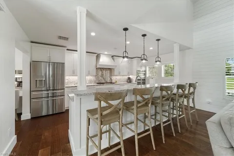 a kitchen with stainless steel appliances kitchen island granite countertop a table chairs stove and refrigerator
