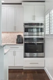 a kitchen with granite countertop white cabinets and stainless steel appliances
