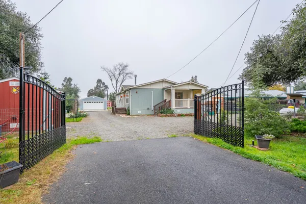a view of a house with a small yard and large trees