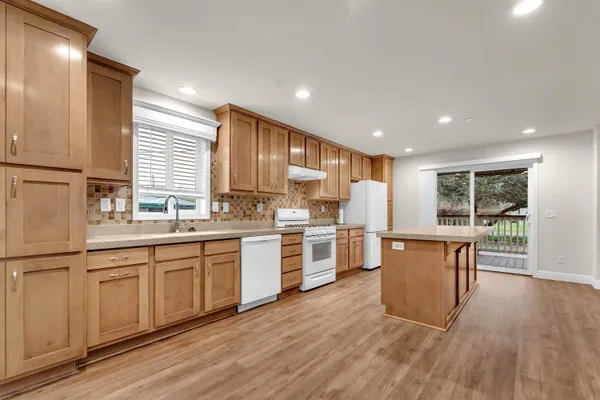 a kitchen with stainless steel appliances granite countertop a stove a refrigerator and a sink with wooden cabinets