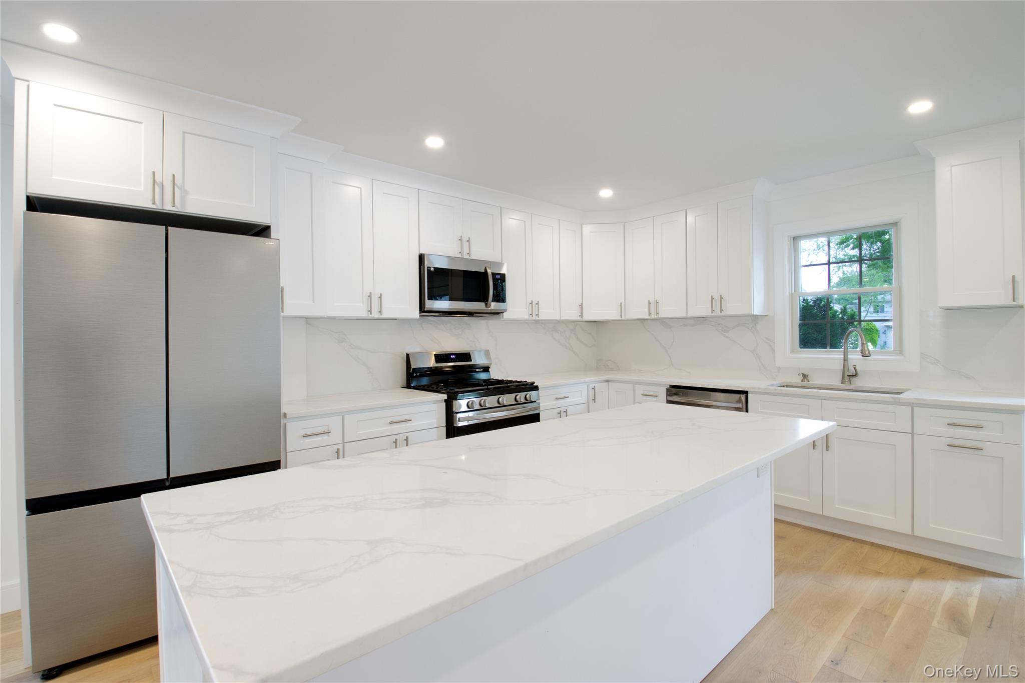 30 Kirkwood Road, Unit B Port Washington, NY 11050 - Photo 12 of 36 a kitchen with white cabinets and stainless steel appliances