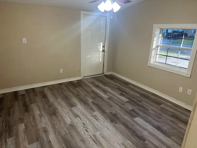 a view of an empty room with wooden floor and a window