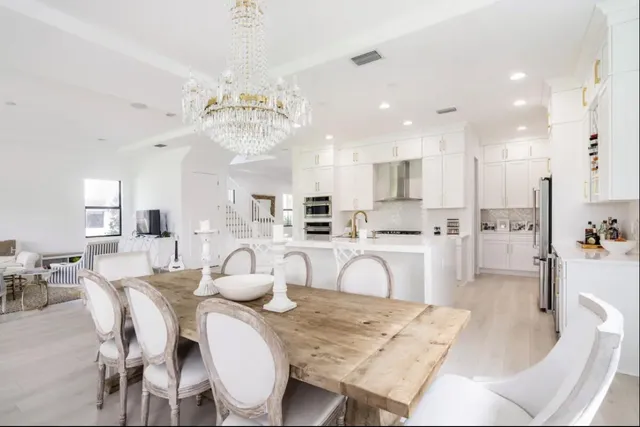 a dining room with kitchen island stainless steel appliances furniture a chandelier and kitchen view
