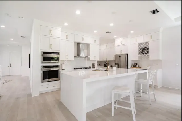 a kitchen with stainless steel appliances kitchen island granite countertop a stove and white cabinets