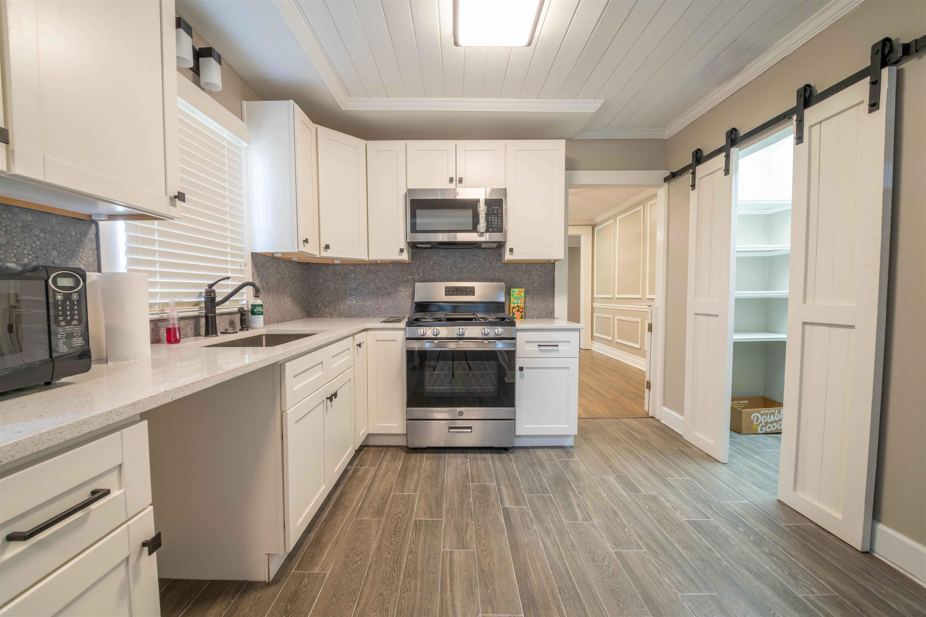 1239 Whitten Road Memphis, TN 38134 - Photo 20 of 24 Kitchen featuring appliances with stainless steel finishes, white cabinetry, wood finish floors, a barn door, and ornamental molding