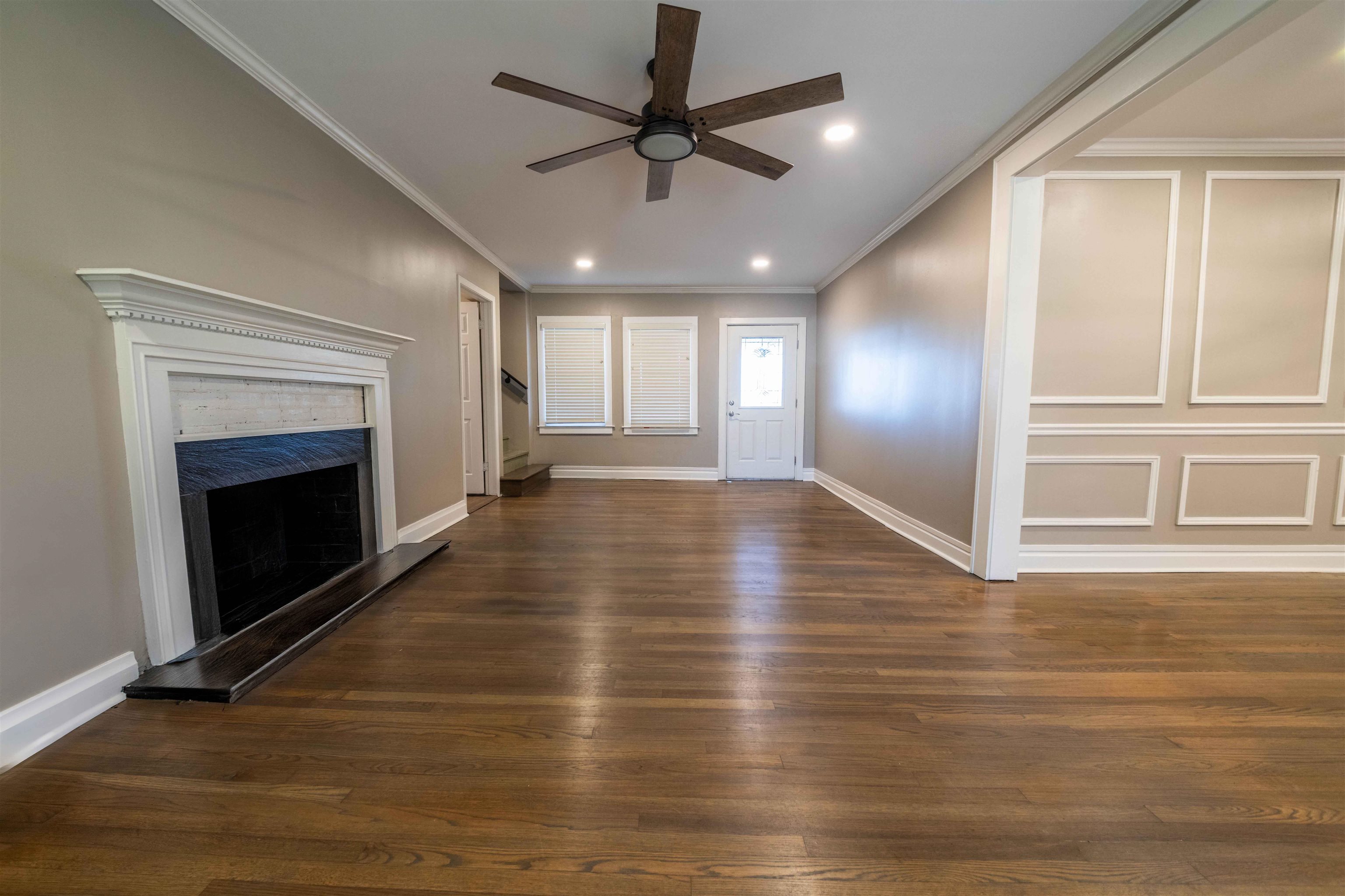 1239 Whitten Road Memphis, TN 38134 - Photo 7 of 24 Unfurnished living room with ornamental molding, a high end fireplace, dark wood finished floors, a decorative wall, and a ceiling fan