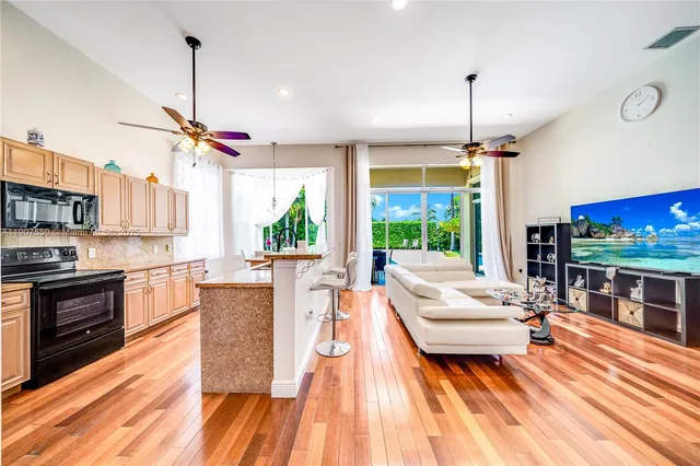 a living room with stainless steel appliances kitchen island granite countertop furniture and a wooden floor