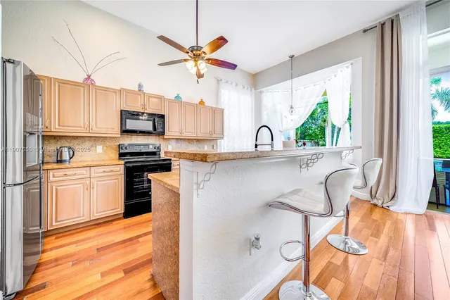 a kitchen with stainless steel appliances a sink a stove a refrigerator cabinets and a window