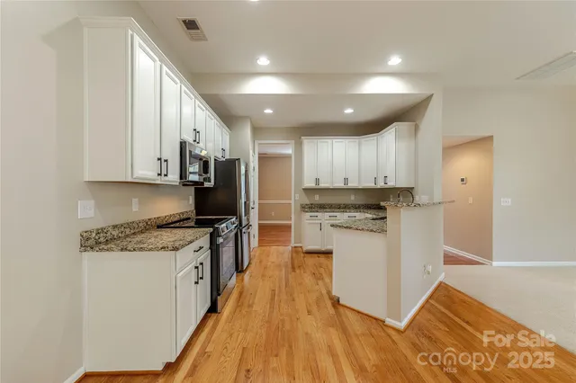 a kitchen with granite countertop a refrigerator a sink dishwasher and a stove with wooden floor