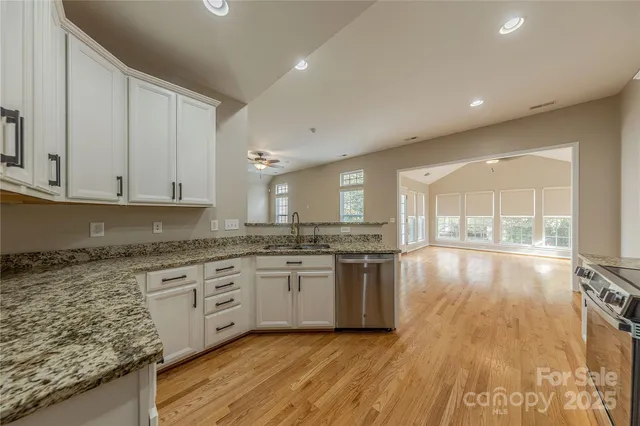 a large kitchen with granite countertop a stove top oven a sink and dishwasher with wooden floor