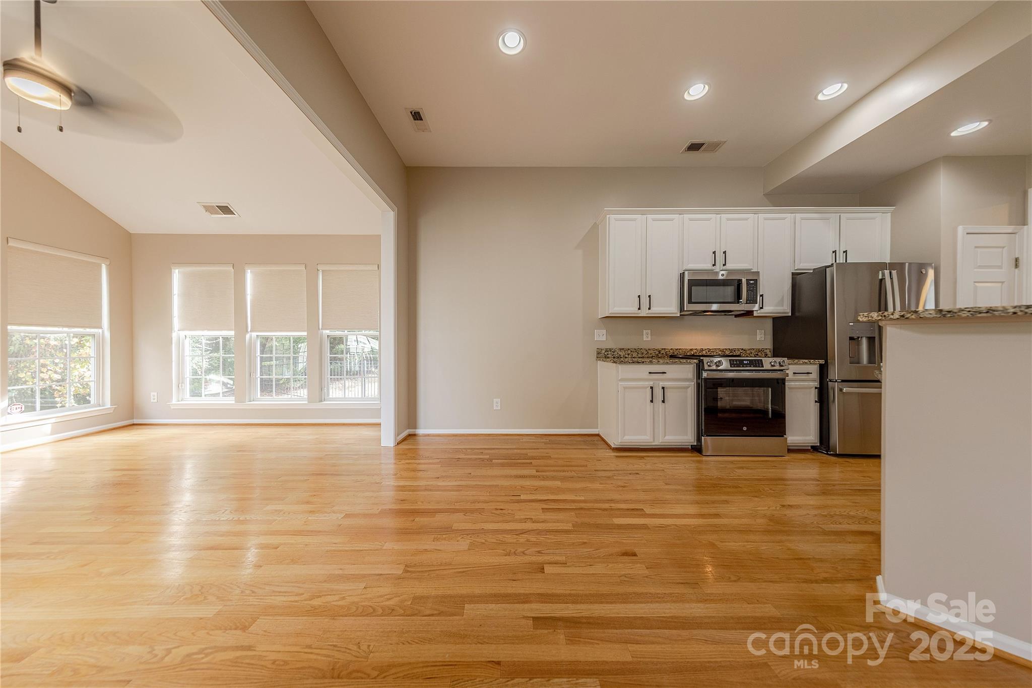 7216 Meyer Road Fort Mill, SC 29715 - Photo 19 of 47 a large kitchen with granite countertop a stove a sink dishwasher a refrigerator and white cabinets with wooden floor