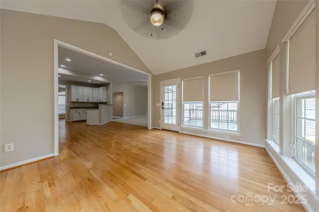 a view of an empty room with a window and wooden floor
