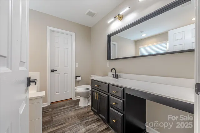 a spacious bathroom with a double vanity sink a mirror and a toilet