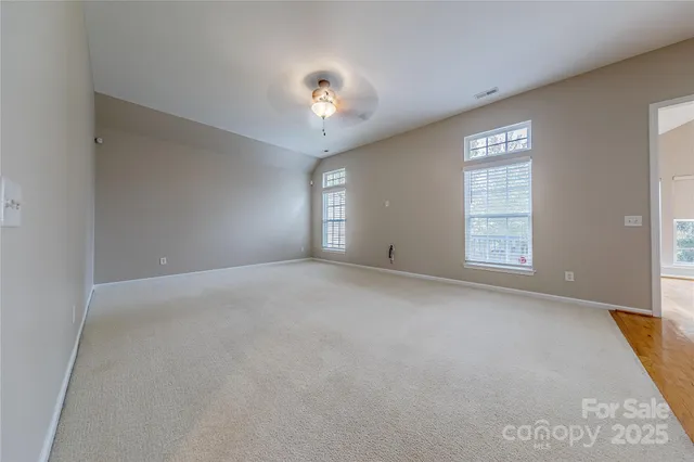 an empty room with windows and chandelier fan