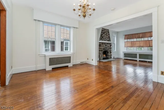 an empty room with wooden floor chandelier and windows