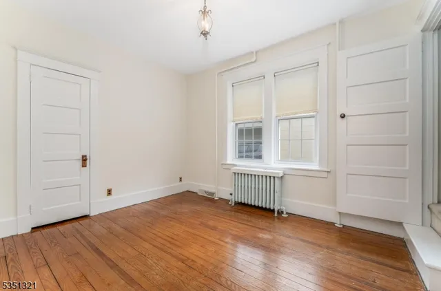 an empty room with wooden floor cabinet and windows