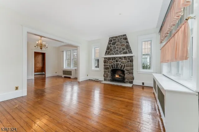 a view of a livingroom with wooden floor a fireplace and windows