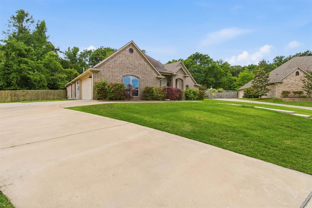 7765 Hickory Spring Lane Tyler, TX 75703 - Photo 3 of 38 Brick exterior residence featuring a gabled roofline, an arched window, and an attached two-car garage